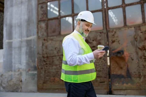 Side view of the senior walking, foreman browsing internet on smartphone and Stock Photos