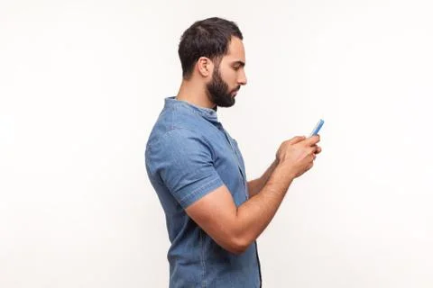 Side view serious assertive man typing on smartphone, betting, using online a Stock Photos