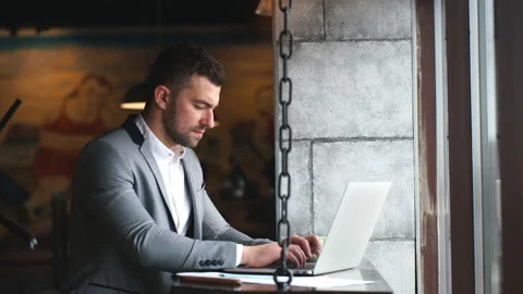 Side view of a serious bearded man entrepreneur sitting with laptop in cafe Stock Footage 88166393