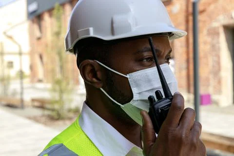Side view of the serious man standing in reflective uniform and protective mask Stock Photos