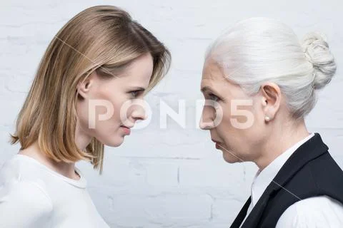 Side view of serious women looking at each other, young and senior people Stock Photos