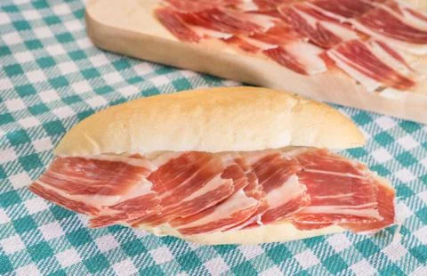 Side view of Serrano ham sandwich over checkered tablecloth 스톡 사진
