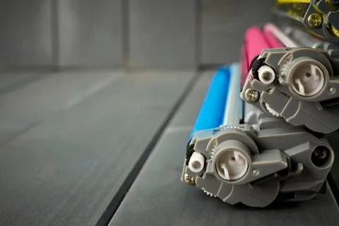 Side view of a set of color laser printer cartridges on gray wooden backgroun Stock Photos