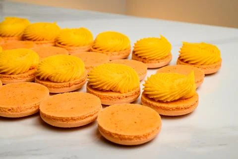 Side view of set of orange fresh macaron dessert halves decorated with mango Foto stock