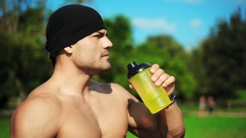 Side view of sexy thirsty bodybuilder drinking water from yellow plastic shaker Stock-Footage 115860237