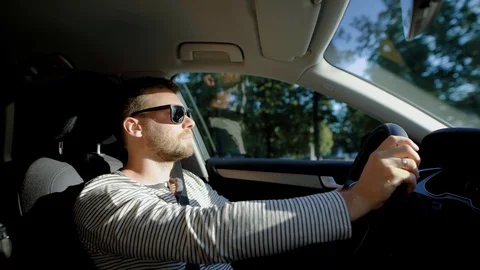 Side view shot of a stylish man driving a car in city in summer. Видео 93865606