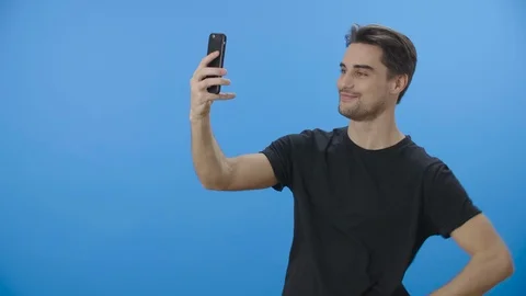 Side view shot of a young man posing playfully while taking selfies - 4K Stock Footage 88399414