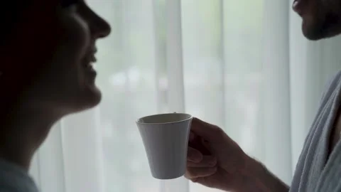 Side view of silhouettes of couple standing near window and drinking coffee Stock Footage 206456670