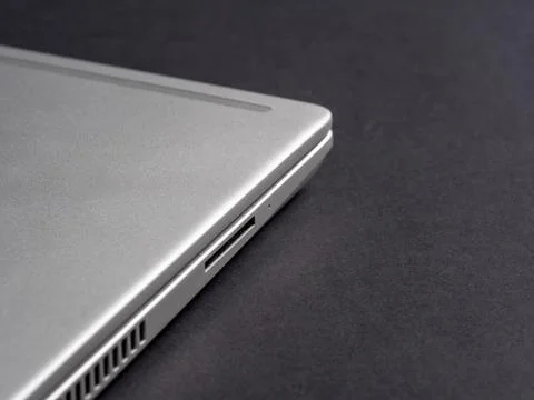 Side view of a silver closed laptop on a dark paper background Stock Photos