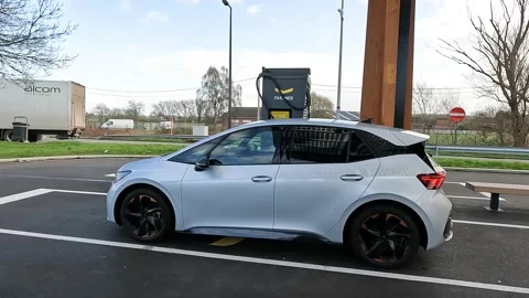 Side view of silver electric car charging at a fast charger next to the highway 스톡 동영상 171615539
