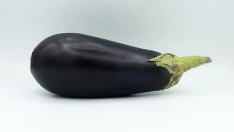 Side view of a single glossy eggplant placed horizontally on a seamless Stock Photos