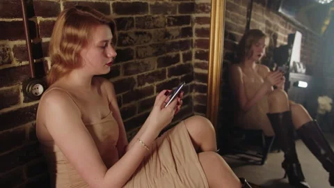 Side view of sitting young blonde woman in dress looking at screen of smartphone Video stock 331886651
