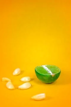 Side view of a slice of lemon surrounded by garlic cloves over a background o Stock Photos