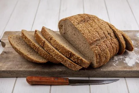 Side view of sliced brown seeded cob on cutting board and knife on wooden b.. Foto stock