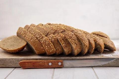 Side view of sliced brown seeded cob on cutting board and knife on wooden s.. Foto stock