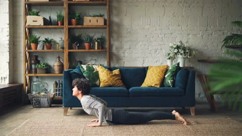 Side view of slim girl doing yoga at home practising Sun Salutation Surya Stock Footage 95832099