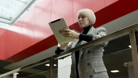 A side view slow motion blonde female executive leaning on a rail in a company's Stock Footage 137820044