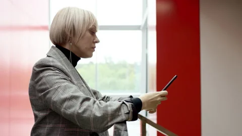 A side view slow motion close up of a blonde business woman leaning on a rail Stock-Footage 135877077