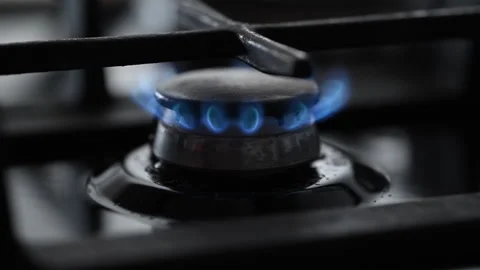 A side-view slow-motion shot of a black gas stove igniting. Stock Footage 318850905