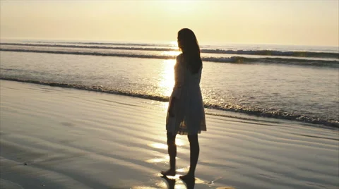 Side view slow motion of young woman walking on wet sea shore at sunset Видео 59070337