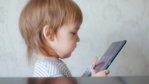 Side view small cute boy toddler holding a digital tablet watching cartoons Stock Footage 150820663