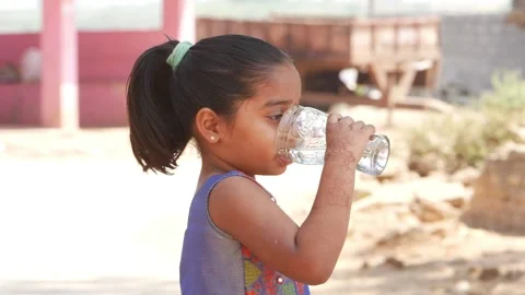 Side view of small girl drinking water from transparent glass Stock Footage 151903764