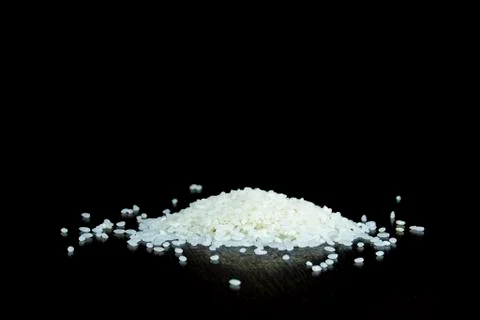 Side view of a small pile of white rice on a dark wood table. Stock Photos