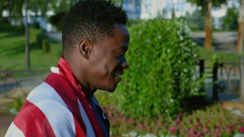 Side view smiling afro-american man walking street with American flag on back Stock Footage 160058892