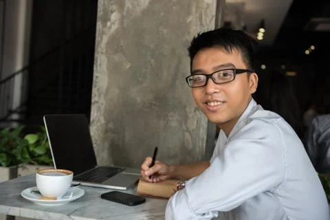 Side view of smiling Asian freelancer writing notes Foto stock