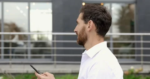 Side view of smiling bearded man walking near modern business center and holding Stock Footage 140684729