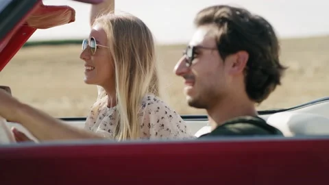 Side view of smiling couple driving in a cabriolet. Video stock 149834592