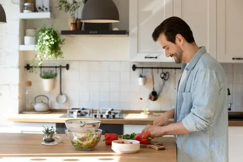 Side view smiling man cutting fresh vegetables, cooking in kitchen Stock Photos