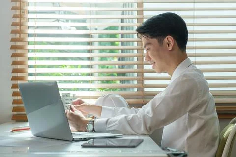 Side view of smiling young architect in shirt working on blueprints at brig.. Stock Photos