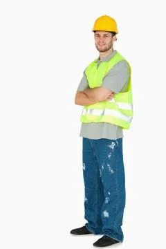 Side view of smiling young construction worker with arms folded Stock Photos