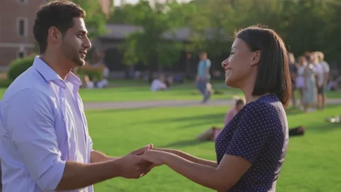 Side view of smiling young multiethnic couple holding hands in summer park Stock Footage 158546685