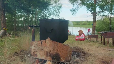 Side view of smokehouse standing on open fire. Cooking meals in touristic camp Stock Footage 144467499