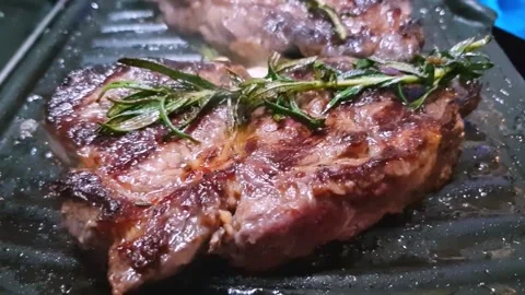 Side view of the Smoking ribeye steak grilled with rosemary, slow motion Stockbeeldmateriaal 130751435