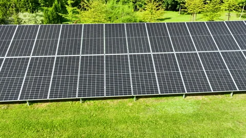 Side view of a solar panel array in a lush green park, emphasizing Stock Footage 286808361