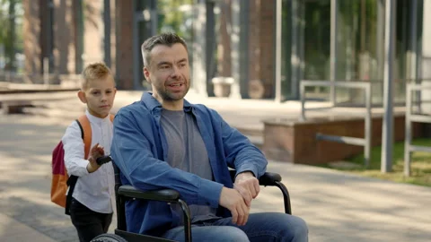 Side view of the son went for a walk with his disable father and pushes his Stock Footage 203892975