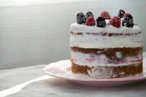 Side view of a sponge cake filled with whipped cream and berries sauce topped Stock Photos