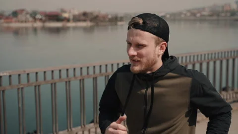 Side view of sportive athletic man run along city river promenade. attractive Stock Footage 130204323