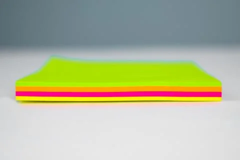 Side view of a stack of different colored paper sticky notes on top of a desk Stock Photos