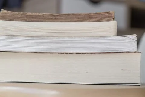 Side view of stacked books of different thicknesses Stock Photos