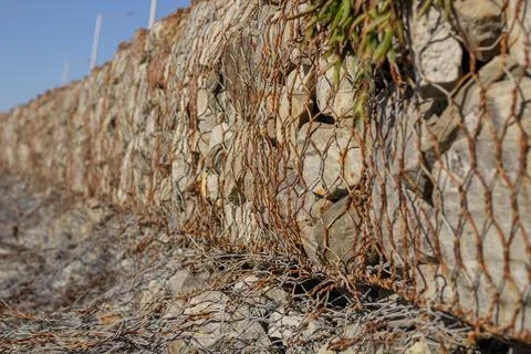 Side view of stone wall contained by metal mesh 写真素材