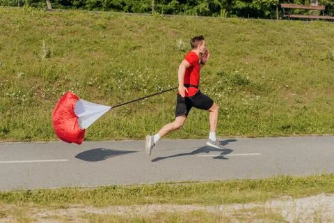 Side view of a strong man doing workout using resistance parachute outdoors Stock Photos