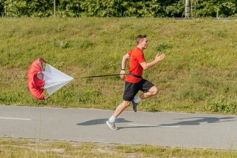 Side view of a strong man doing workout using resistance parachute outdoors Foto stock