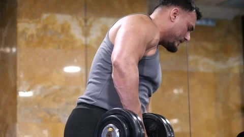Side view of a strong muscular man performing bent over dumbbell rows for b.. Vidéo 344031982