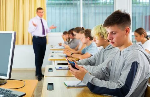 Side view of student group working with mobile phones in class Foto stock