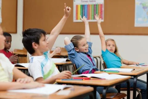 Side view of students raising hands Stock Photos