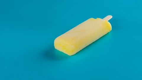 Side view studio shoot yellow popsicle melting and reverse time lapse Stock Footage 92985687